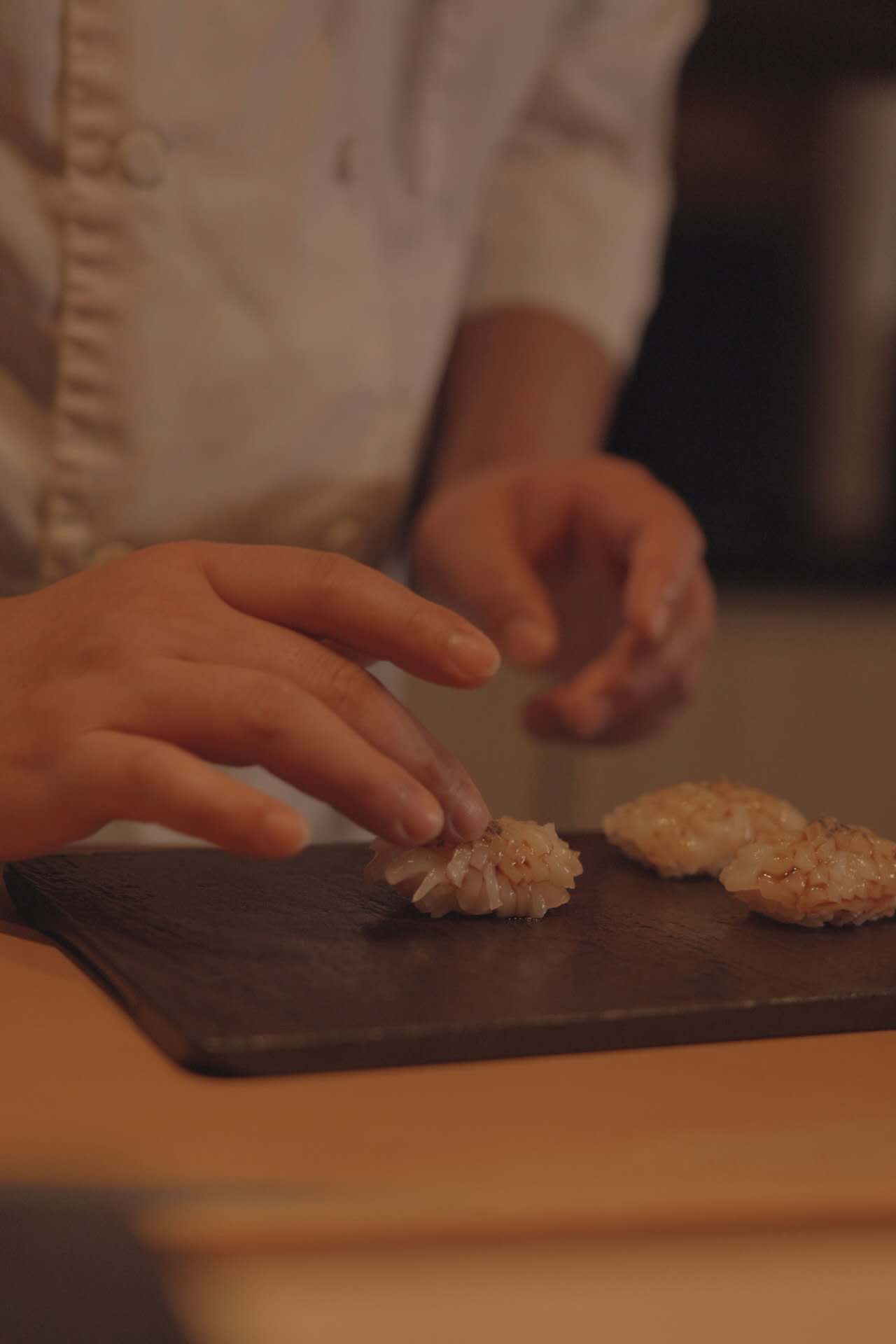 Chef brushing nikiri glaze as the final touch on nigiri