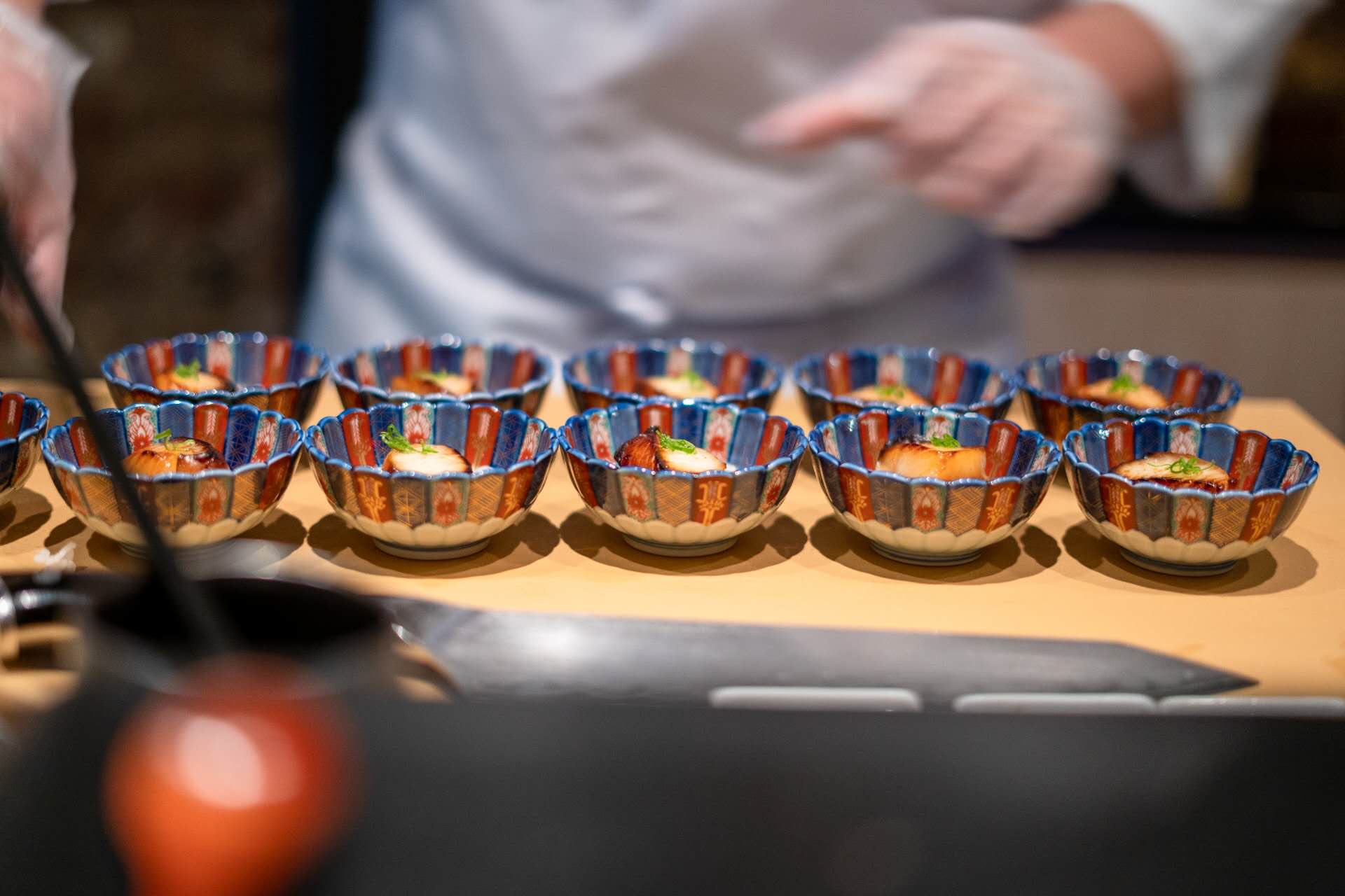 Chef preparing appetizer bowls during live sushi performance at Kiyoshi Omakase