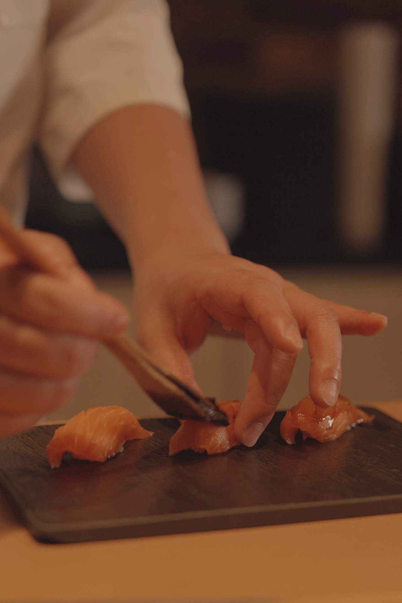 Chef slicing fresh salmon during live omakase performance