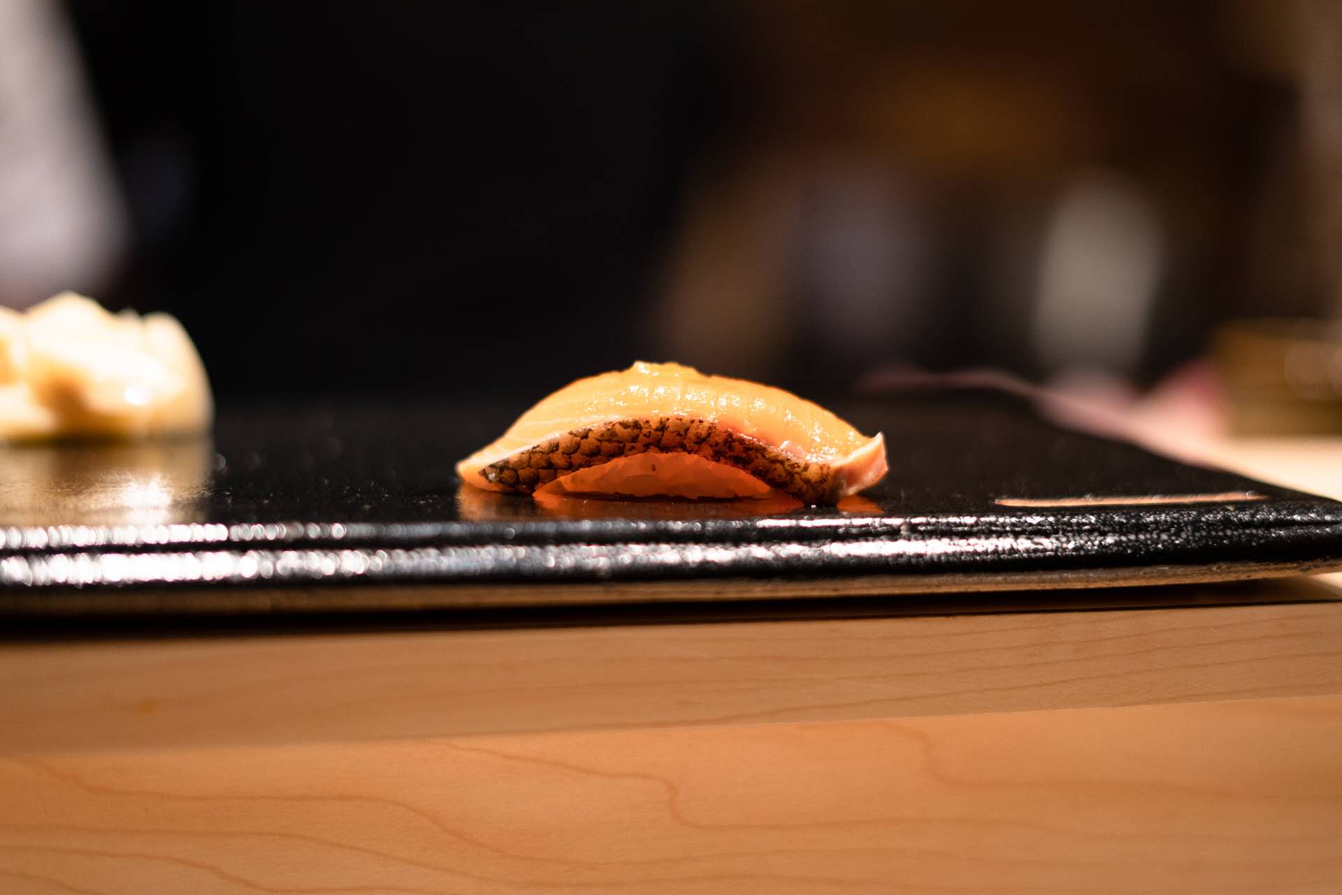 Perfectly formed salmon nigiri on black slate showing rice technique