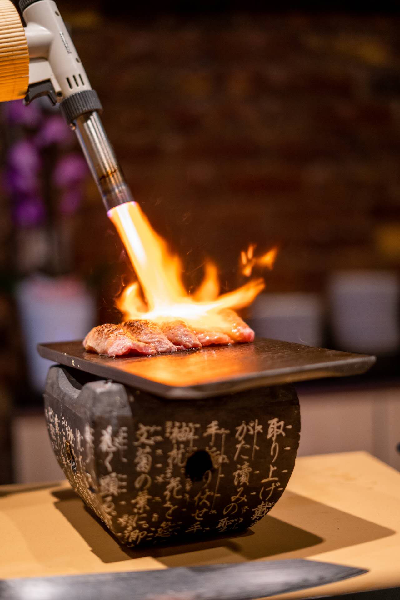 Closeup of chef torching wagyu beef at the omakase counter